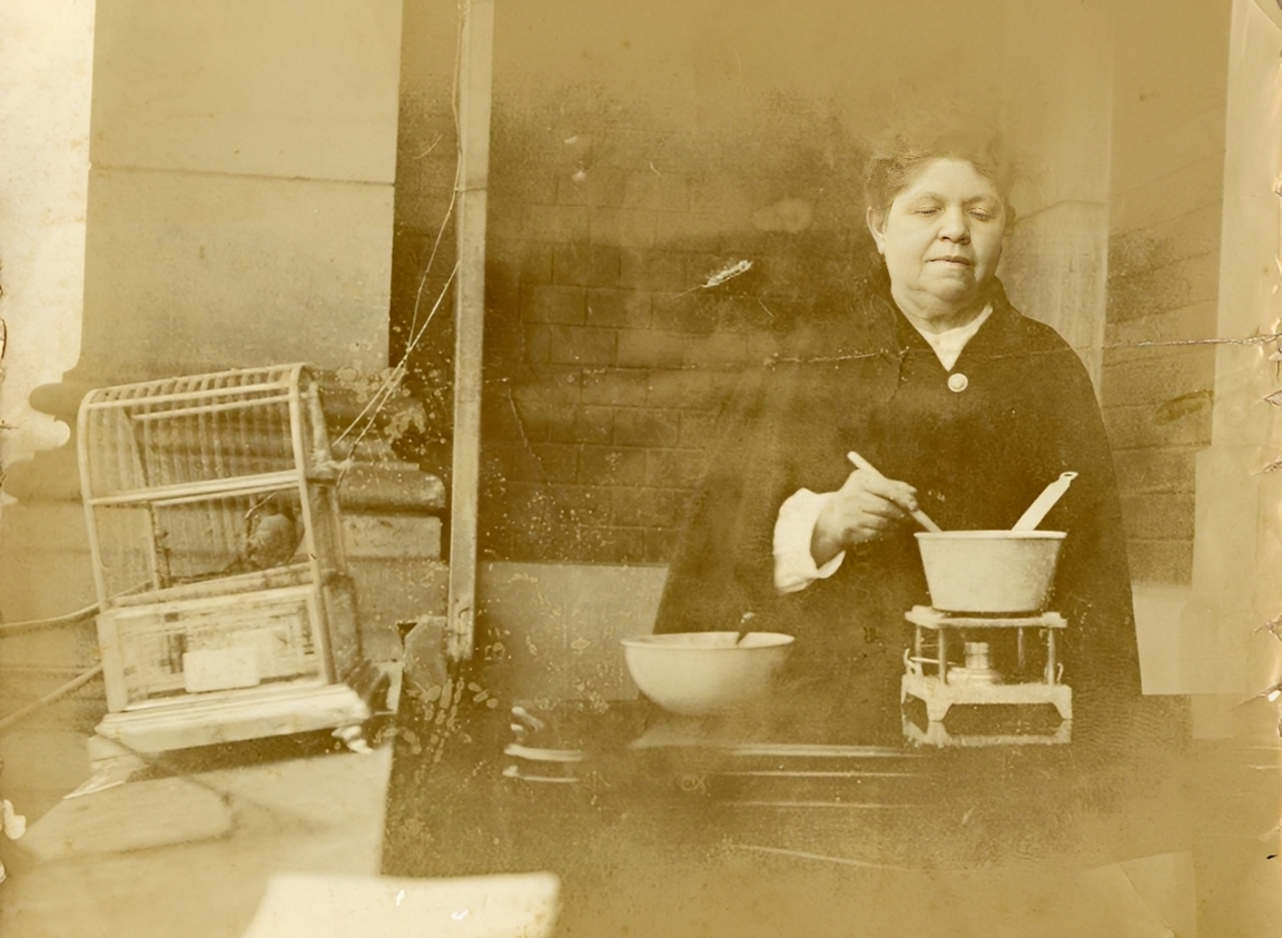 Mulher junto a utensílios e uma gaiola.