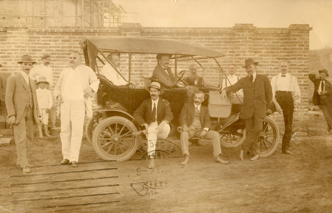 Grupo de pessoas reunido em torno de um automóvel.